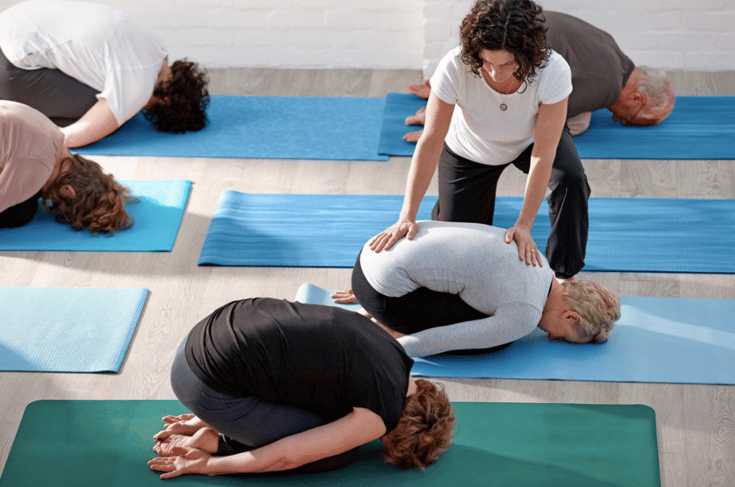 Yoga teacher adjusting in Childs pose.png